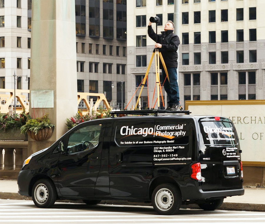 Chicago architectural photographer standing on a van roof platform using a Berlebach ash wood tripod to capture a high-angle building shot.